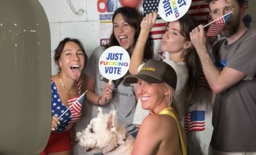 Runners posing with flags and vote signs at the Run to Register photo booth